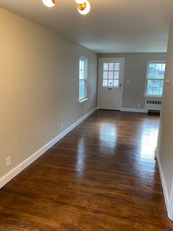 empty room featuring radiator heating unit and dark hardwood / wood-style flooring