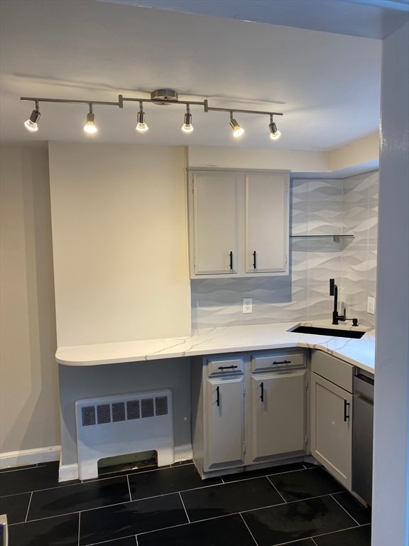 kitchen featuring white cabinets, backsplash, radiator, stainless steel dishwasher, and sink