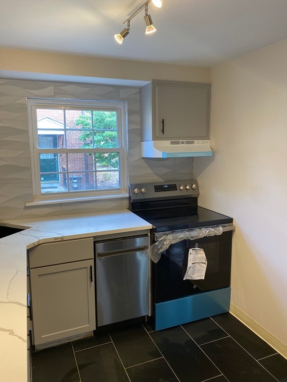 kitchen with appliances with stainless steel finishes, backsplash, dark tile patterned floors, and ventilation hood