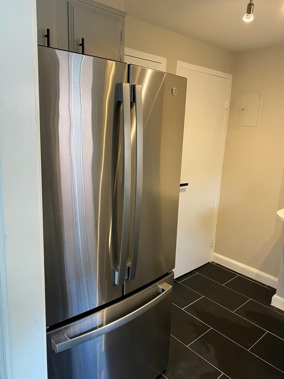 details with stainless steel refrigerator and dark tile patterned flooring