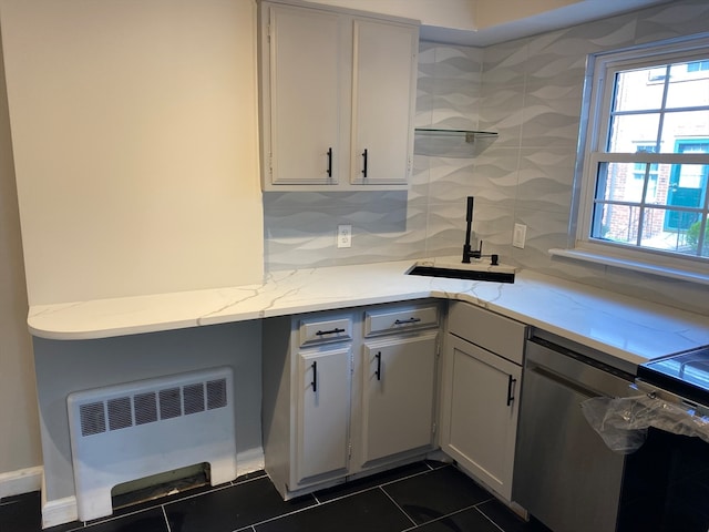 kitchen featuring radiator, sink, dark tile patterned floors, stainless steel dishwasher, and backsplash