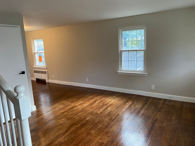 unfurnished room featuring radiator heating unit, plenty of natural light, and dark hardwood / wood-style flooring