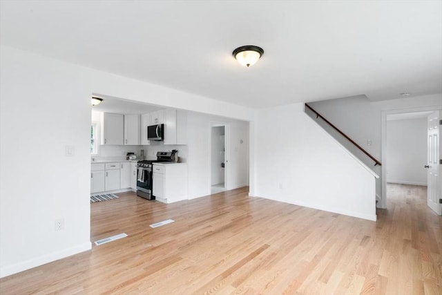 691 Beacon St, Lowell, MA 01850 - unfurnished living room featuring light wood-style floors and stairs