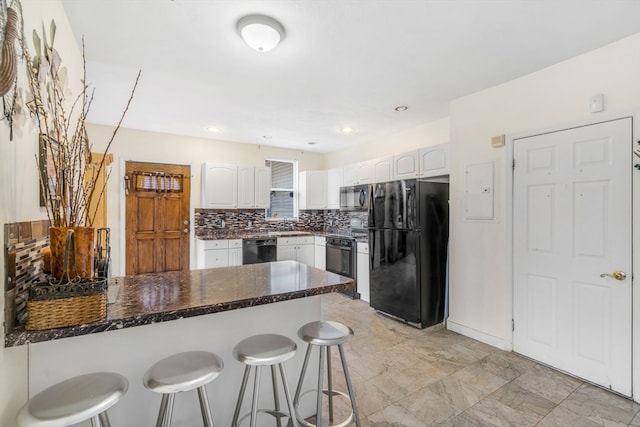 kitchen with white cabinetry, a breakfast bar area, light tile patterned floors, black appliances, and decorative backsplash