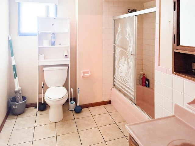 bathroom featuring tile patterned flooring, toilet, vanity, baseboards, and combined bath / shower with glass door