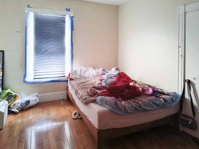 bedroom with wood-type flooring and baseboards