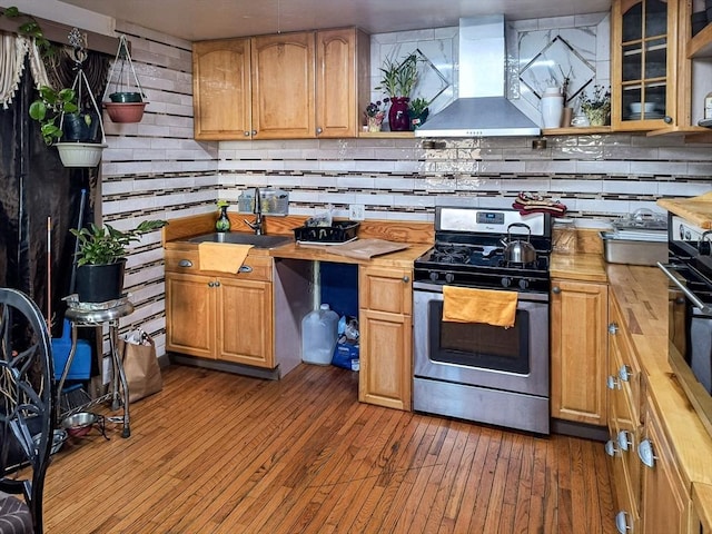 kitchen featuring open shelves, a sink, gas range, butcher block countertops, and wall chimney exhaust hood