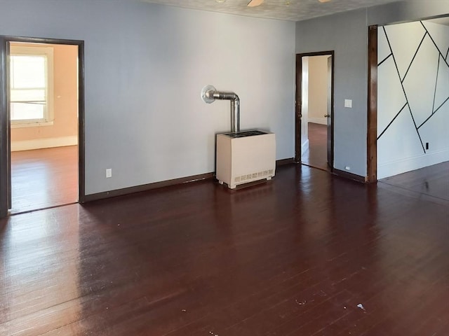 unfurnished room with baseboards, heating unit, and wood finished floors