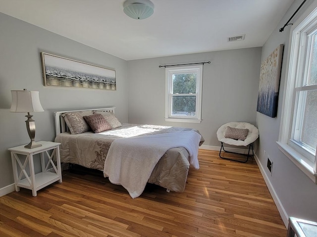 bedroom featuring wood finished floors, visible vents, and baseboards