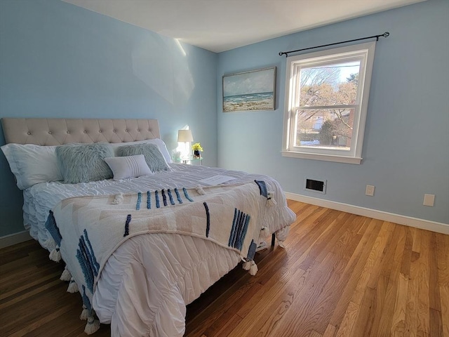 bedroom with visible vents, baseboards, and wood finished floors