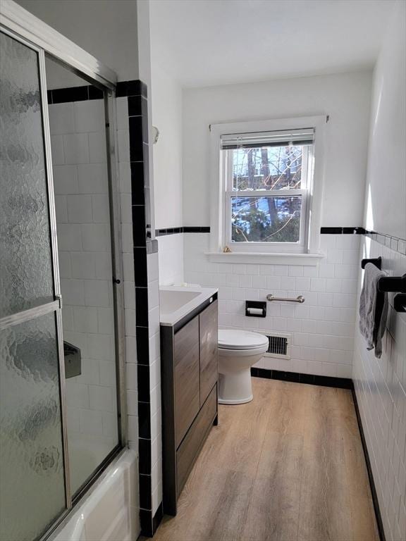 full bath featuring visible vents, tile walls, vanity, and wood finished floors