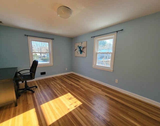 unfurnished office featuring wood finished floors, visible vents, and baseboards