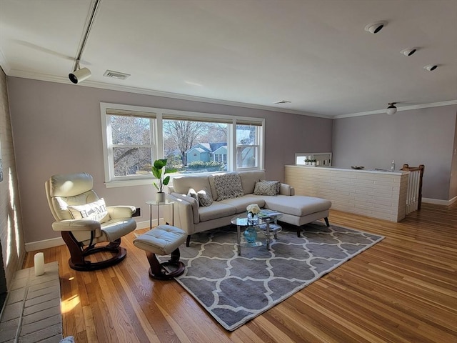 living room featuring visible vents, baseboards, wood finished floors, and ornamental molding