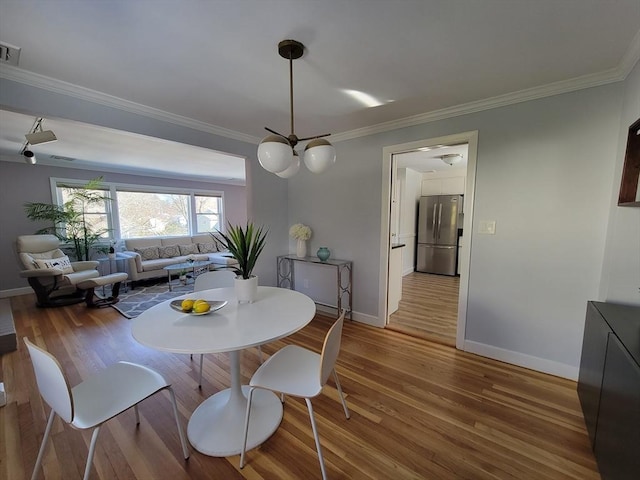 dining space featuring crown molding, wood finished floors, baseboards, and visible vents