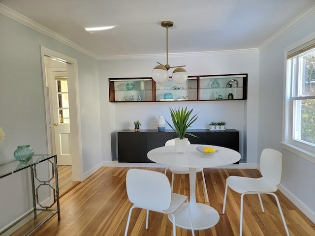 dining space with light wood finished floors, crown molding, and a wealth of natural light