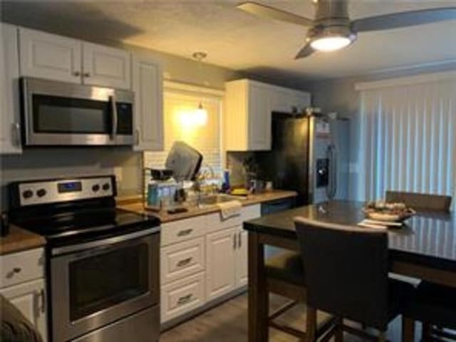 kitchen featuring stainless steel appliances, ceiling fan, and white cabinets