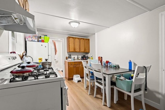 48-50 Portland St, Haverhill, MA 01830 - kitchen with white appliances, range hood, brown cabinets, light wood-style flooring, and light countertops
