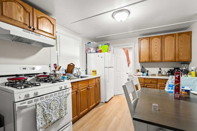48-50 Portland St, Haverhill, MA 01830 - kitchen with white appliances, under cabinet range hood, light wood-style floors, and brown cabinetry