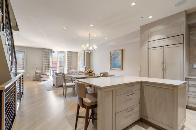 kitchen featuring recessed lighting, a center island, light wood finished floors, a chandelier, and light countertops