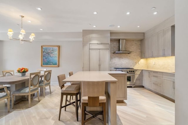 kitchen featuring wall chimney exhaust hood, an inviting chandelier, high end stainless steel range oven, backsplash, and a center island