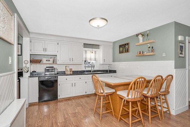 kitchen featuring sink, a breakfast bar area, light hardwood / wood-style flooring, dishwasher, and white cabinetry