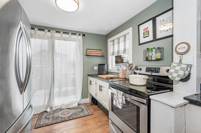 kitchen with appliances with stainless steel finishes, white cabinets, and light wood-type flooring