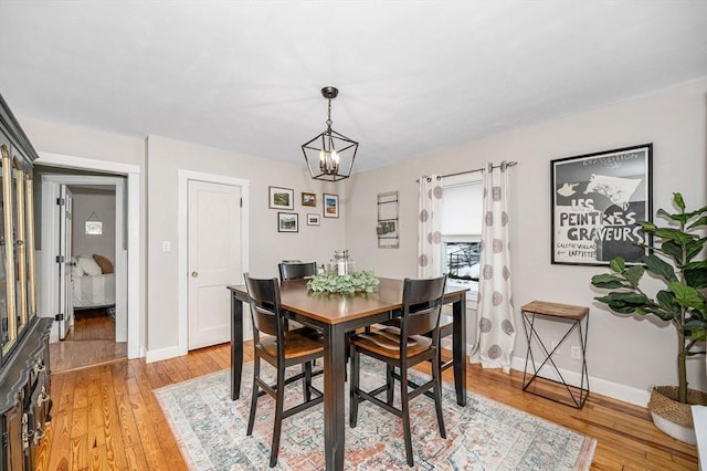 dining space with light hardwood / wood-style flooring and a chandelier