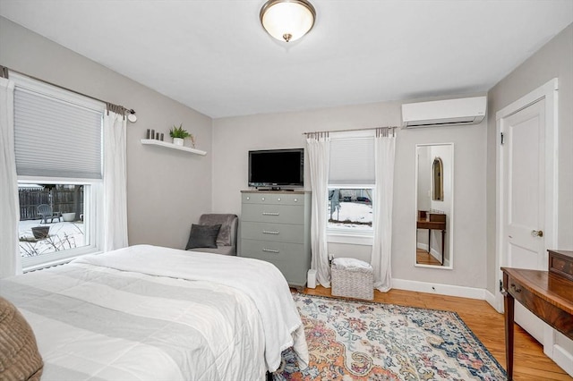 bedroom featuring multiple windows, a wall unit AC, and light hardwood / wood-style flooring