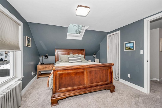 bedroom with light carpet, radiator heating unit, and vaulted ceiling with skylight