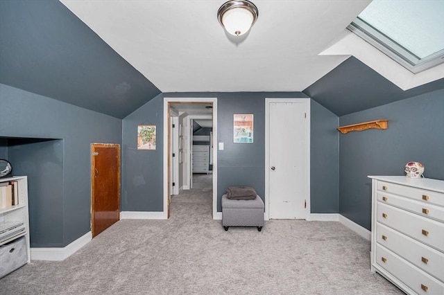 interior space with vaulted ceiling with skylight and light colored carpet