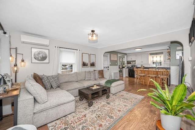 living room with sink, hardwood / wood-style floors, and an AC wall unit