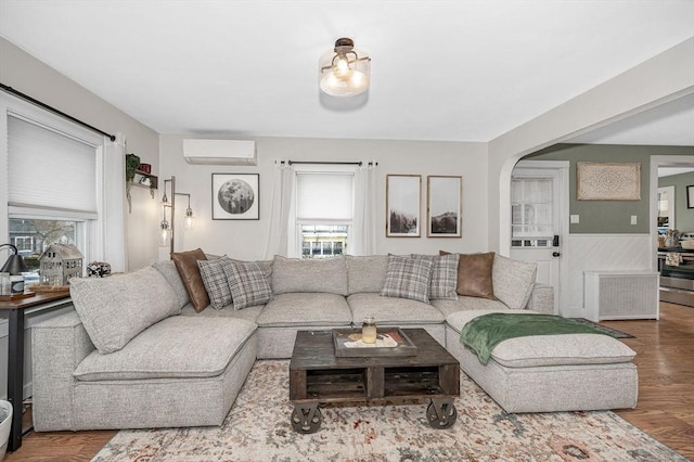 living room featuring a healthy amount of sunlight, radiator heating unit, wood-type flooring, and a wall mounted AC