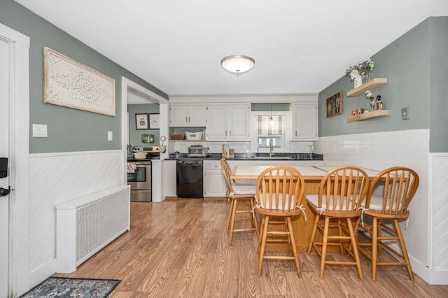 kitchen with a breakfast bar, dishwasher, white cabinetry, stainless steel electric stove, and light wood-type flooring