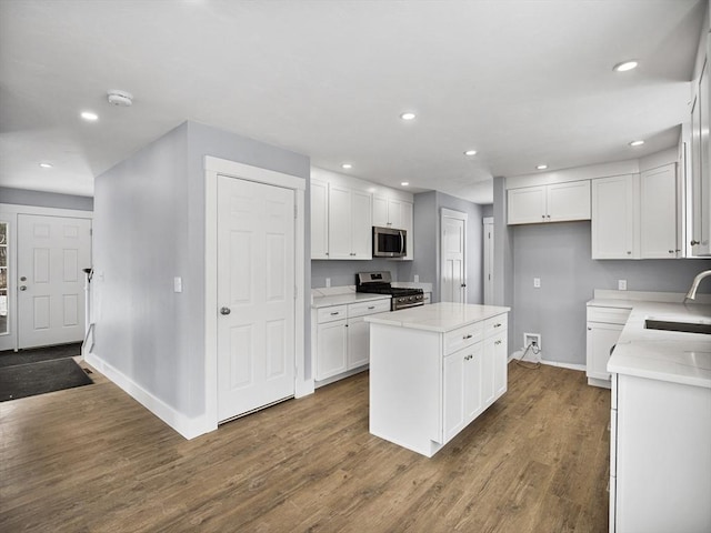 kitchen featuring dark wood-type flooring, sink, white cabinetry, a kitchen island, and stainless steel appliances