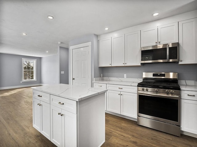 kitchen featuring stainless steel appliances, dark hardwood / wood-style floors, white cabinets, and a kitchen island