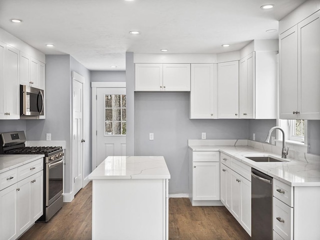 kitchen featuring stainless steel appliances, a center island, sink, and white cabinets