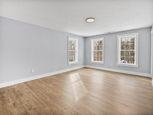 spare room featuring a healthy amount of sunlight and light hardwood / wood-style floors