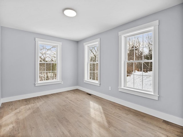 unfurnished room featuring hardwood / wood-style flooring and a wealth of natural light