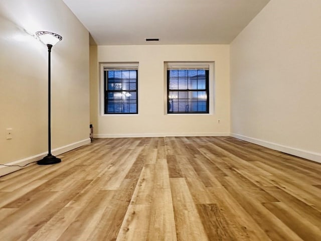 spare room featuring visible vents, baseboards, and wood finished floors