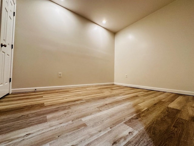 spare room with baseboards, wood finished floors, and recessed lighting