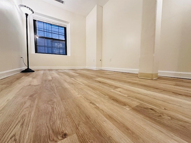 unfurnished room with light wood-type flooring, visible vents, and baseboards