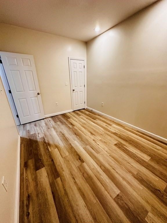 unfurnished room with light wood-type flooring and baseboards