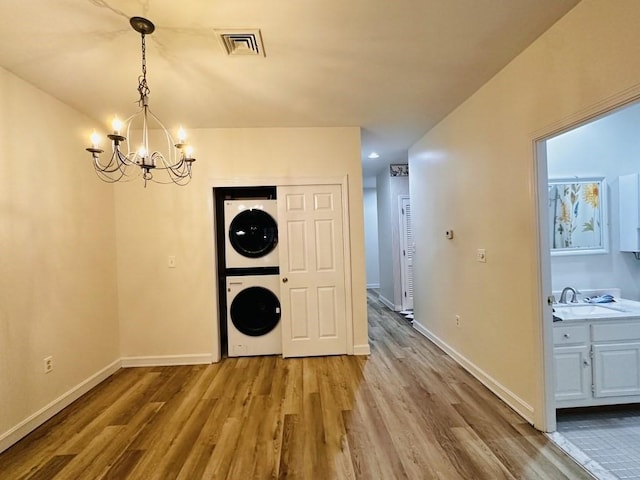 unfurnished dining area with stacked washer and dryer, visible vents, baseboards, and wood finished floors