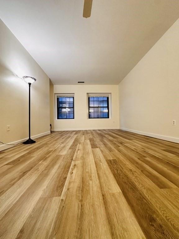 unfurnished living room featuring light wood-type flooring, a ceiling fan, and baseboards