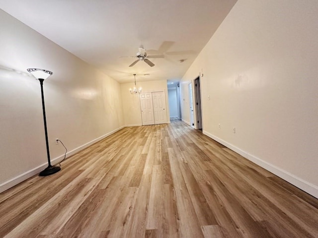 interior space featuring ceiling fan with notable chandelier, light wood finished floors, and baseboards