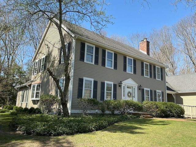 colonial-style house with a chimney and a front yard