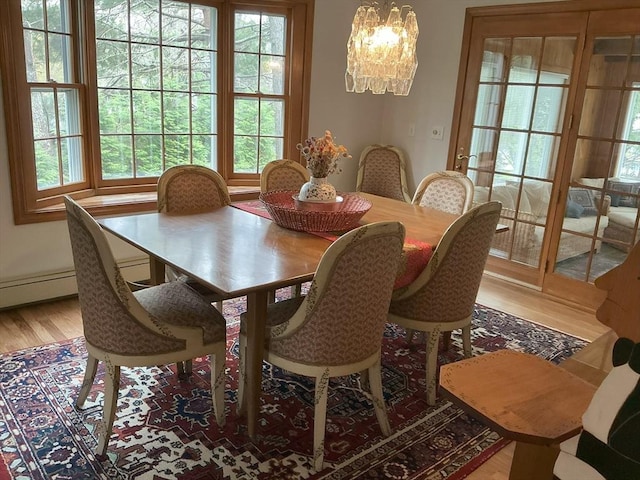 dining space with an inviting chandelier, a wealth of natural light, and light wood-style flooring