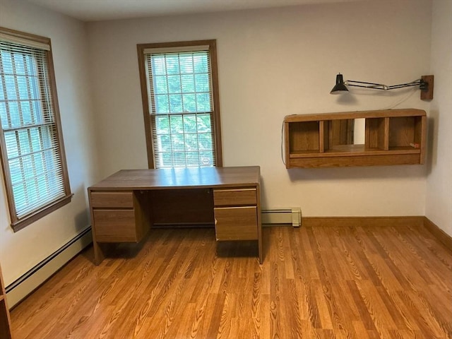 unfurnished office with a healthy amount of sunlight, a baseboard heating unit, and light wood-type flooring