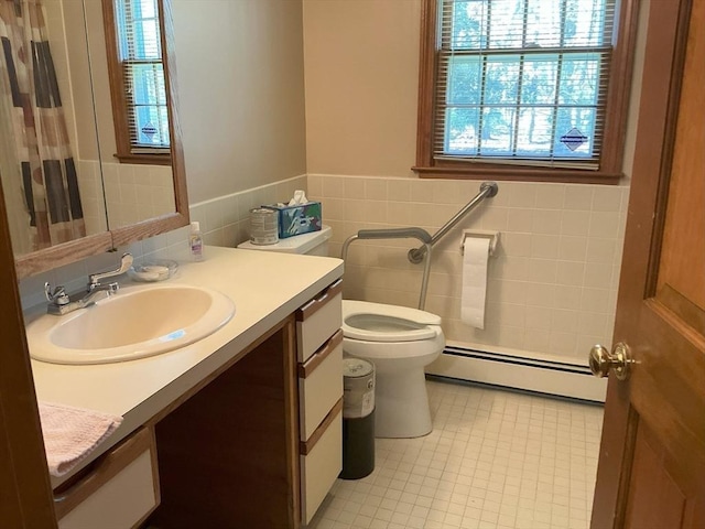 bathroom with tile walls, baseboard heating, curtained shower, vanity, and toilet
