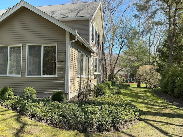 view of side of property featuring a lawn and roof with shingles